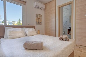 Une chambre à coucher avec un grand lit, une armoire en bois et une salle de bain visible à travers une porte ouverte.