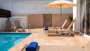 A poolside area with lounge chairs, a table, and an umbrella. - Narcissos Villa 3 - Three Bedroom Villa, Sleeps 8 (Protaras)