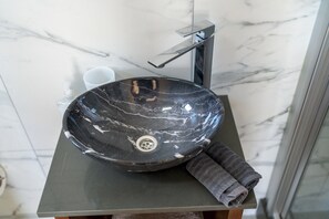 A black marble sink with a faucet on a dark countertop in a bathroom.