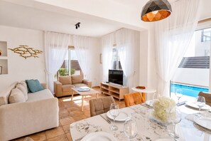 A modern living room with a sofa, coffee table, and a dining area set for a meal.