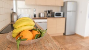 A kitchen with a wooden countertop, a bowl of fruit, and a microwave in the background. - Narcissos Villa 3 - Three Bedroom Villa, Sleeps 8 (Protaras)