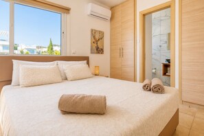 A hotel room with a large bed, a painting on the wall, and a view of the city.