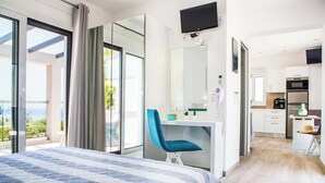 Moderni hotellihuone, jossa on suuri sänky, työpöytä tuolilla, televisio ja näkymä ulos.