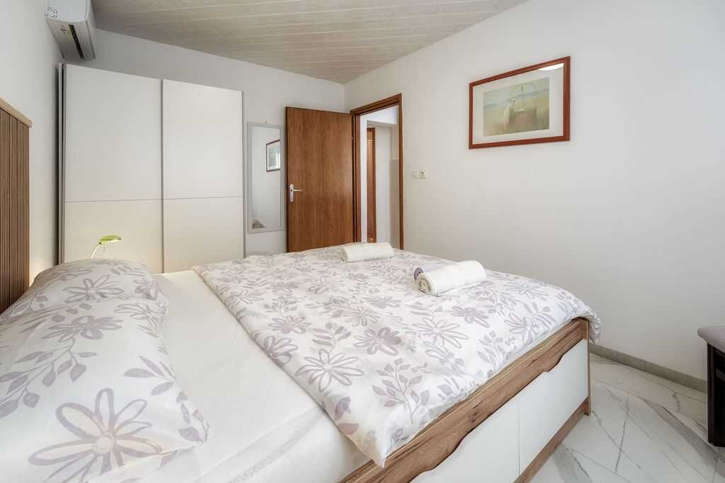 A bedroom with a bed, a wardrobe, a door, and a framed picture on the wall.