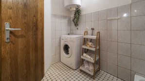 Ein kleines Badezimmer mit Waschmaschine, Handtuchhalter und Toilettenpapierhalter.