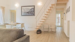 A modern living room with a staircase, a dining area, and a framed picture on the wall. - The Sweet Square Flat (Varenna)