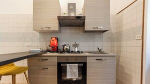 Une cuisine compacte équipée d’un four encastré, d’une cuisinière à gaz et d’un évier.