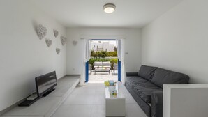 Ein modernes Wohnzimmer mit Fernseher, grauem Sofa, Couchtisch und dekorativer Wandgestaltung.