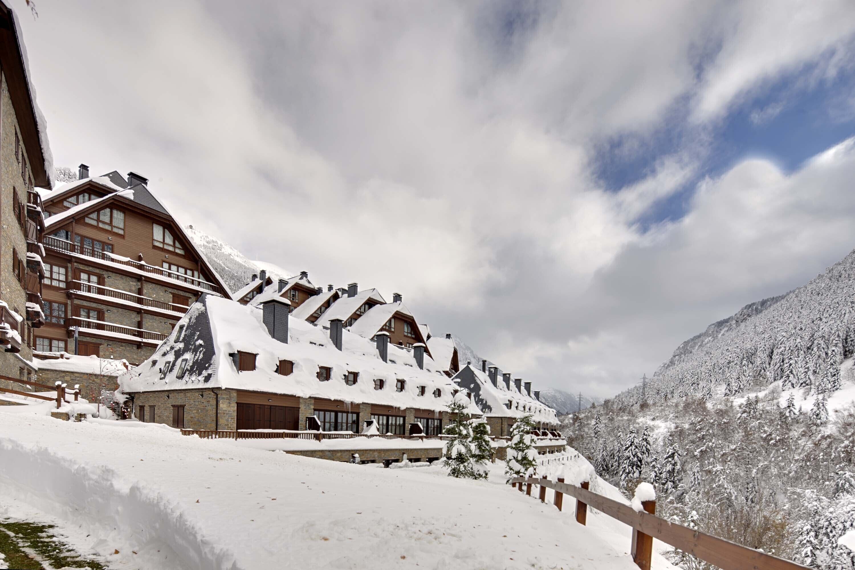 A snow-covered building with multiple balconies and a mountain backdrop.