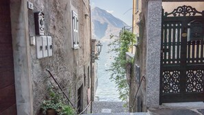 A narrow stone staircase leading to a water body with a mountain in the background. - Elizabeth House Varenna (Varenna)