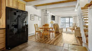 A modern kitchen with a black refrigerator, wooden cabinets, and a dining area with a table and chairs.