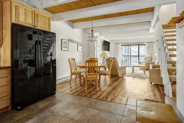 A modern kitchen with a black refrigerator, wooden cabinets, and a dining area with a table and chairs.