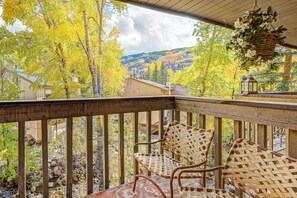 A wooden deck with wicker chairs and a hanging basket. - Tranquil Creek Getaway | Free Vail Shuttle (Vail)