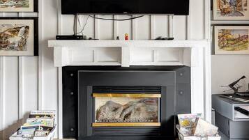 A fireplace with a stone surround, a flat-screen TV mounted above, and framed artwork on the walls.