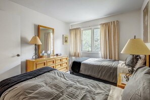 A bedroom with two beds, a dresser, a mirror, and a window with curtains. - Tranquil Creek Getaway | Free Vail Shuttle (Vail)