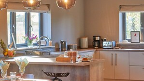 A modern kitchen with a central island, stainless steel appliances, and a view of the outdoors.
