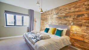 A bedroom with a large bed, a wooden wall, and a window with curtains.