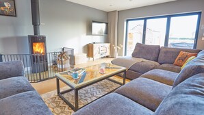 A modern living room with a fireplace, comfortable seating, a coffee table, and a television.