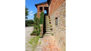 Una scala di pietra conduce a un edificio in mattoni con una finestra e una porta.