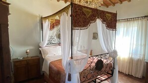 Un letto a baldacchino con tenda, un lampadario e un soffitto in legno rustico.