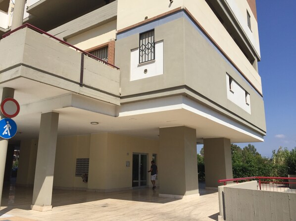 A multi-story building with a flat facade, large pillars, and a covered entrance area.