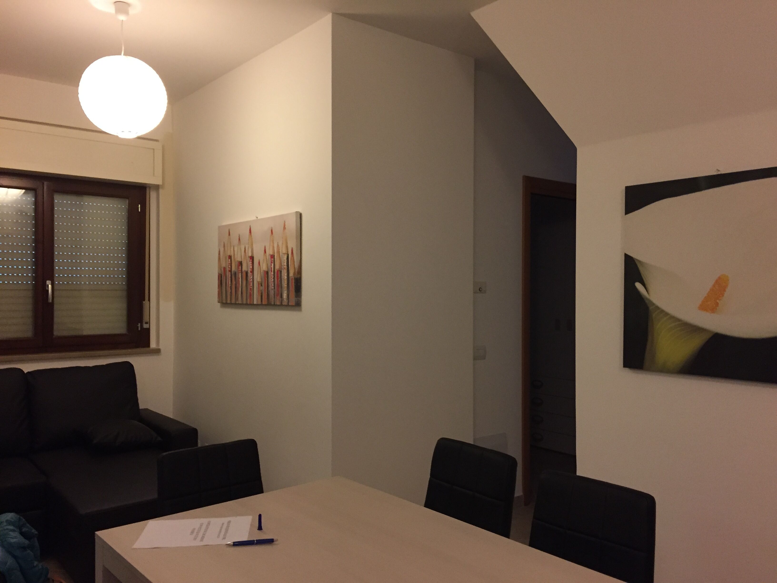 A modern conference room with a long table, several chairs, a painting on the wall, and a ceiling light.