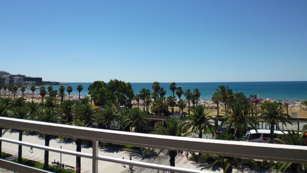 Ein Balkon mit Blick auf einen Strand, Palmen und das Meer.