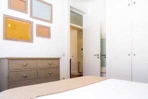 Une chambre à coucher avec un lit, une commode, une armoire et des tableaux encadrés accrochés au mur.
