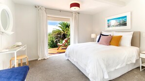Un dormitorio con cama, escritorio, silla y vistas a zonas verdes.