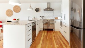 Una cocina moderna con armarios blancos, una estufa de acero inoxidable y un horno empotrado.