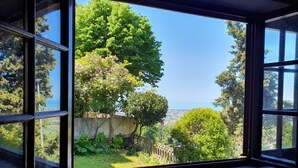 A view through a window with a clear sky, greenery, and a distant landscape. - Santa Lucia Suite, apartment with lovely view over the shore (Santa Lucia)