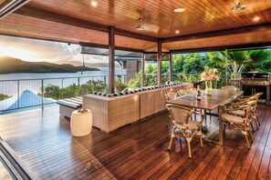 A wooden deck with a dining area, outdoor seating, and a view of a lake.