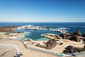 A coastal resort with multiple swimming areas surrounded by rocky formations and clear blue waters. - Modern holiday home with breathtaking sea views, spacious terrace (Arco Da Calheta)