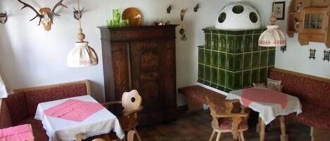 Un comedor rústico con mesas y bancos de madera, un muro con azulejos verdes y diversas decoraciones en las paredes, incluyendo monturas de animales.