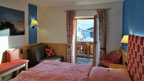 A hotel room with a bed, a sofa, a desk, and a view of the outside. - 2-room vacation apartment, approx. 45sqm with sunny south-facing balcony (Reit im Winkl)