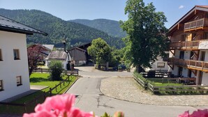 A village street with traditional buildings, a cobblestone circle, and a mountain backdrop. - 2-room vacation apartment, approx. 45sqm with sunny south-facing balcony (Reit im Winkl)