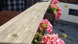 A wooden table with pink flowers, a plaid cushion, and a sign reading "Haus Zauner" against a white wall. - 2-room vacation apartment, approx. 45sqm with sunny south-facing balcony (Reit im Winkl)