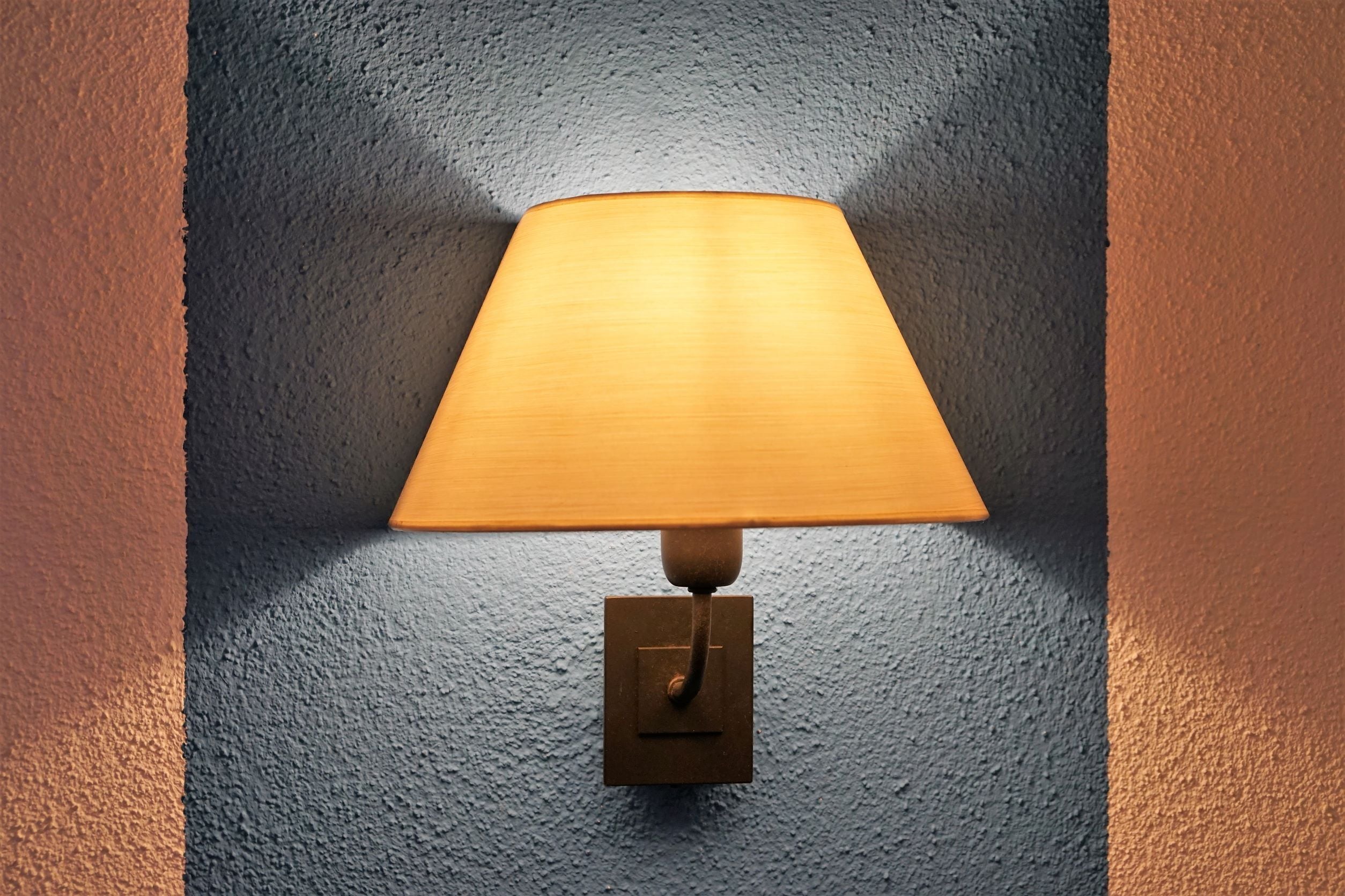 Una lámpara de pared con base de madera y pantalla de tela.