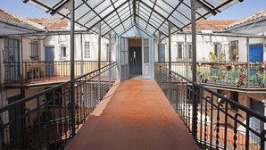 Un pasaje cubierto con piso de ladrillo, barandas de metal y techo de cristal.