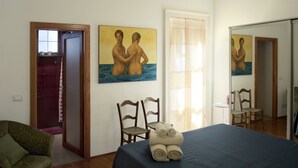 Une chambre d’hôtel avec un lit, deux chaises, un tableau et un miroir.