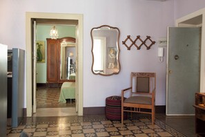 A room with a patterned floor, a wooden chair, a mirror, and a door.