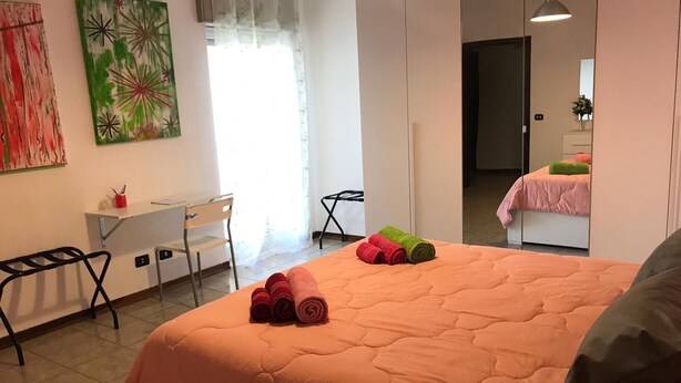 A modern bedroom with a large bed, a desk, and a chair. - Paolo Suite in via Parioli in Gela (Gela)