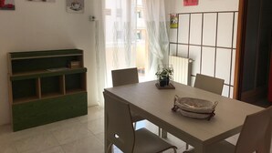 A dining area with a table and chairs, a green bench, a potted plant, and artwork on the walls. - Paolo Suite in via Parioli in Gela (Gela)