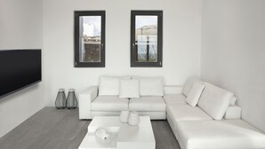 Un salon moderne avec un canapé d’angle blanc, une table basse blanche et deux fenêtres à cadres noirs.