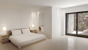Une chambre moderne avec un grand lit, des lampes de chevet, un miroir et une vue sur un mur en pierre, visible à travers une porte-fenêtre coulissante.