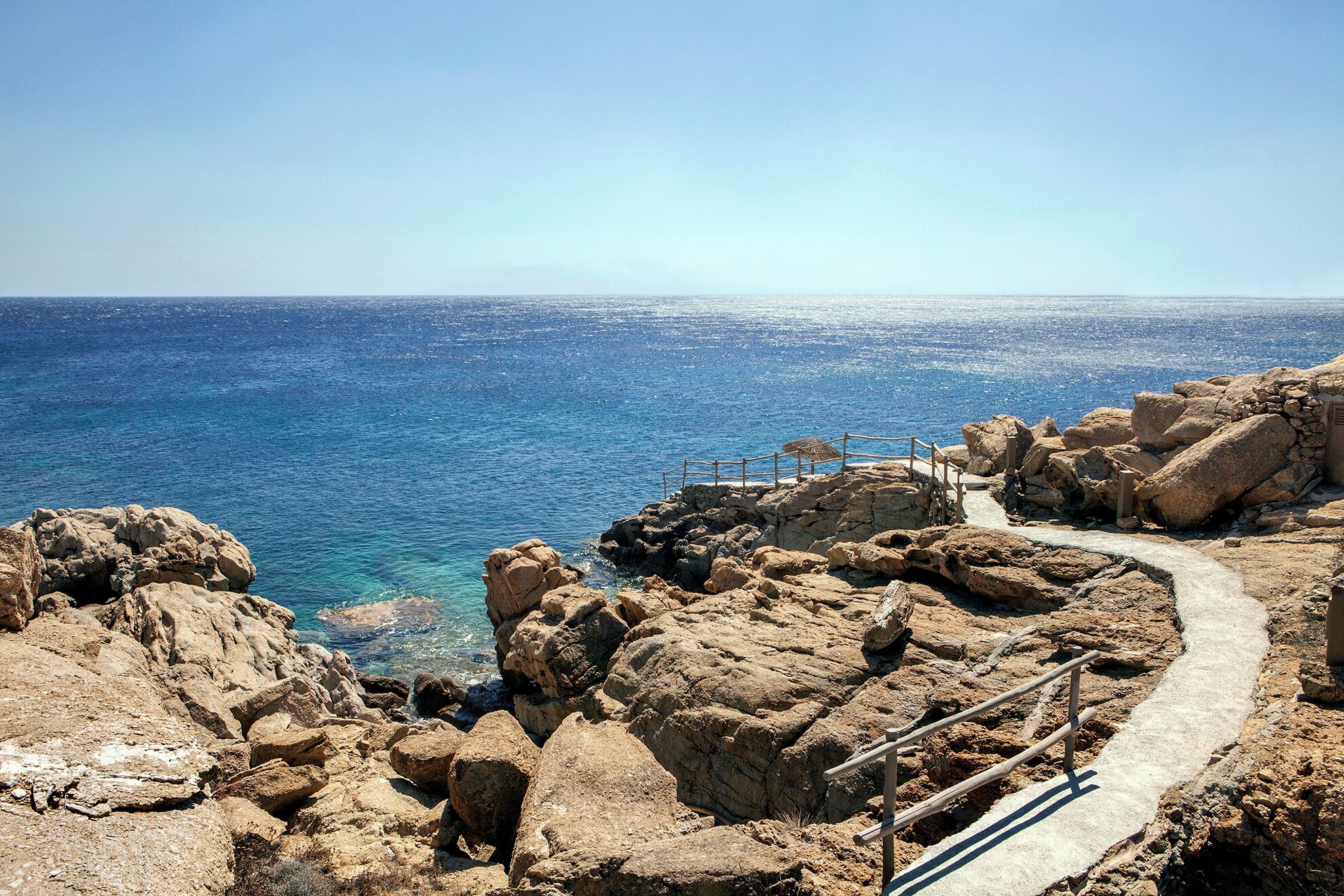 A rocky coastal path leading to a viewpoint overlooking the sea.