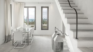 Un intérieur moderne avec un coin repas, de grandes fenêtres et un escalier.