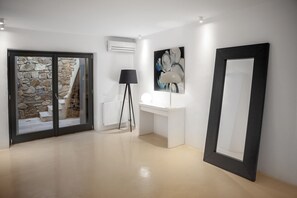 A modern interior with a stone wall, a white desk with a lamp, and a large framed artwork on the wall.
