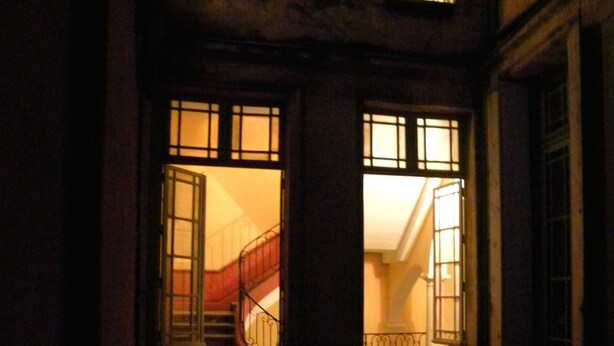 Ein mehrgeschossiges Gebäude mit beleuchteten Fenstern und einer Treppe.