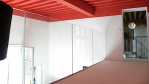 Ein modernes Interieur mit roter Decke, großen Fenstern und einer Treppe, die zu einer oberen Ebene führt.